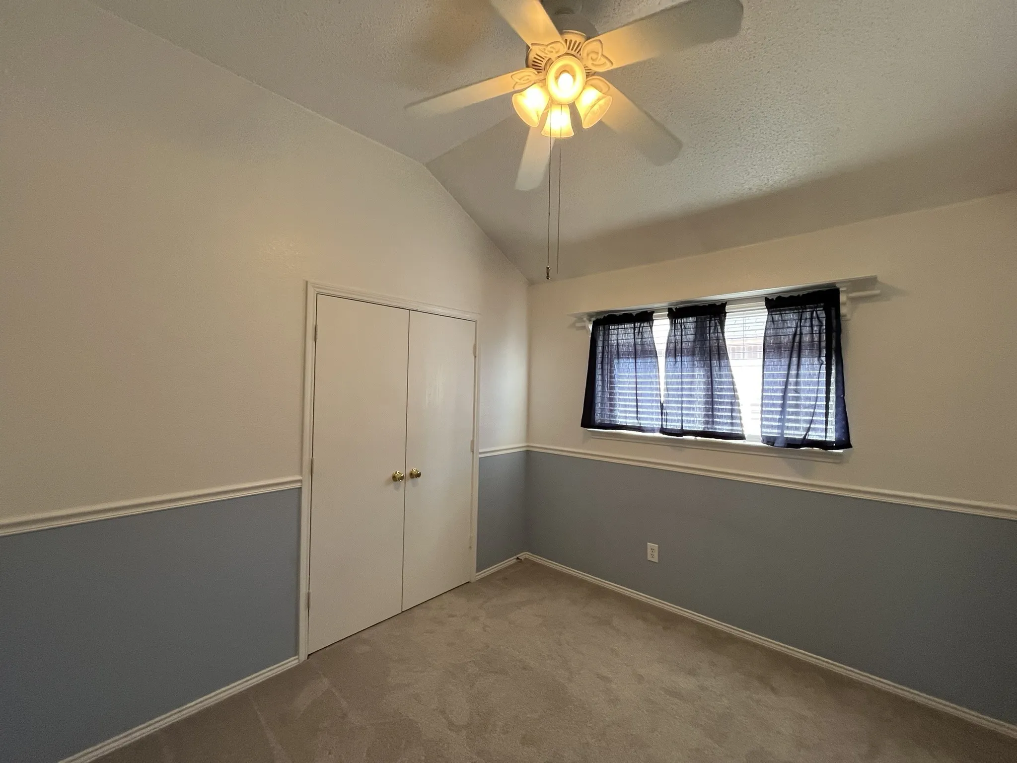 Vaulted ceiling with ceiling fan, dual-tone wall treatment, window with blinds, and carpeted flooring