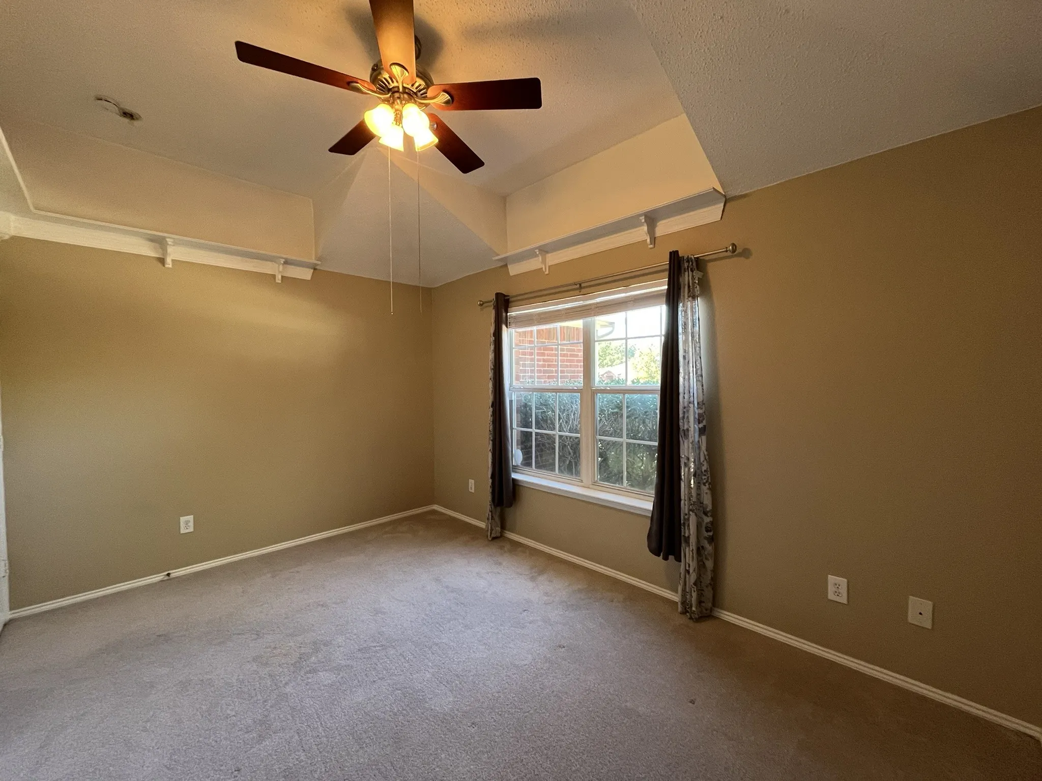 Vaulted ceiling with a ceiling fan light fixture, carpet flooring, and a multi-pane window