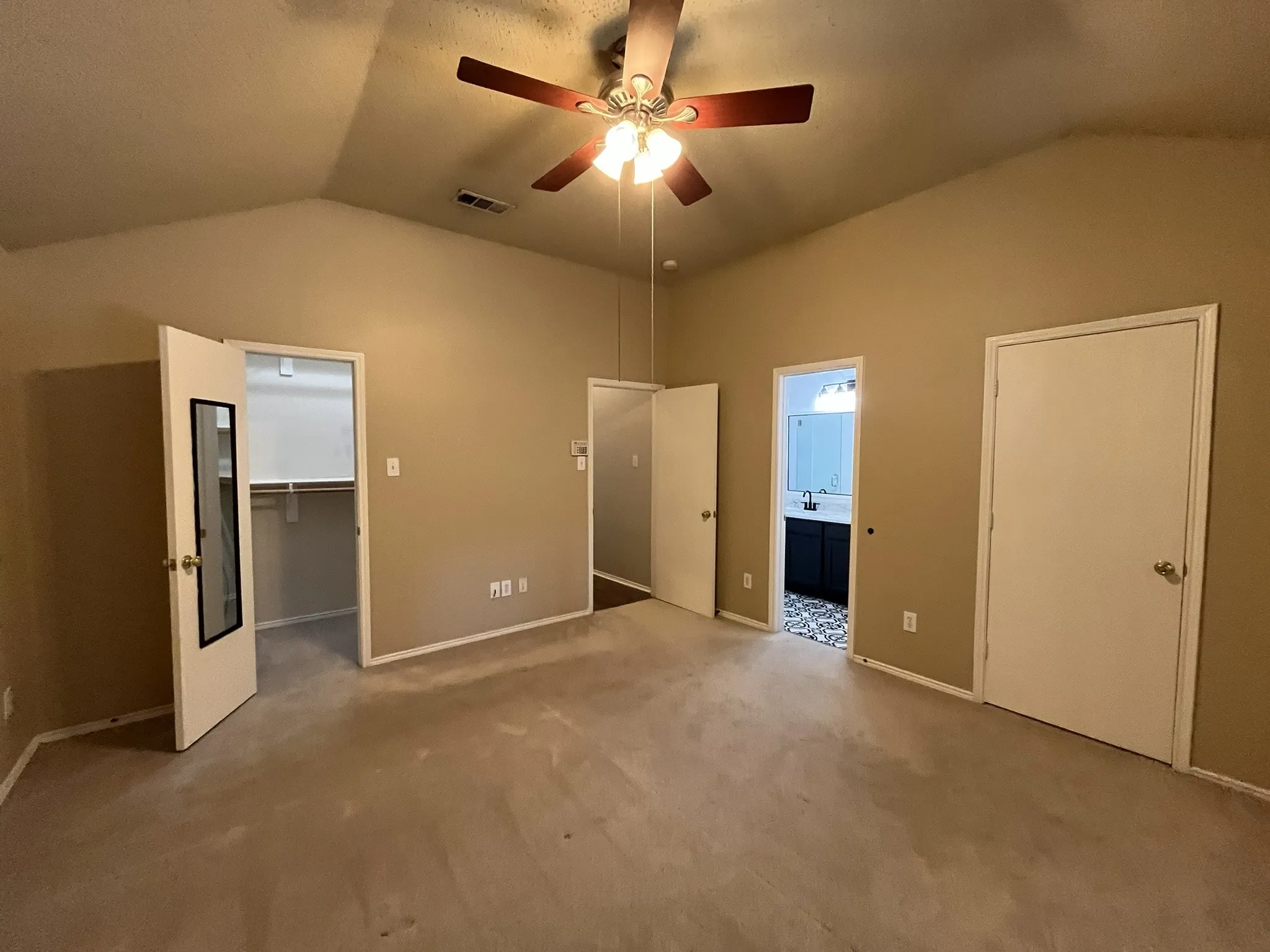 Vaulted ceilings with a ceiling fan, carpet flooring, and a walk-in closet with built-in shelving