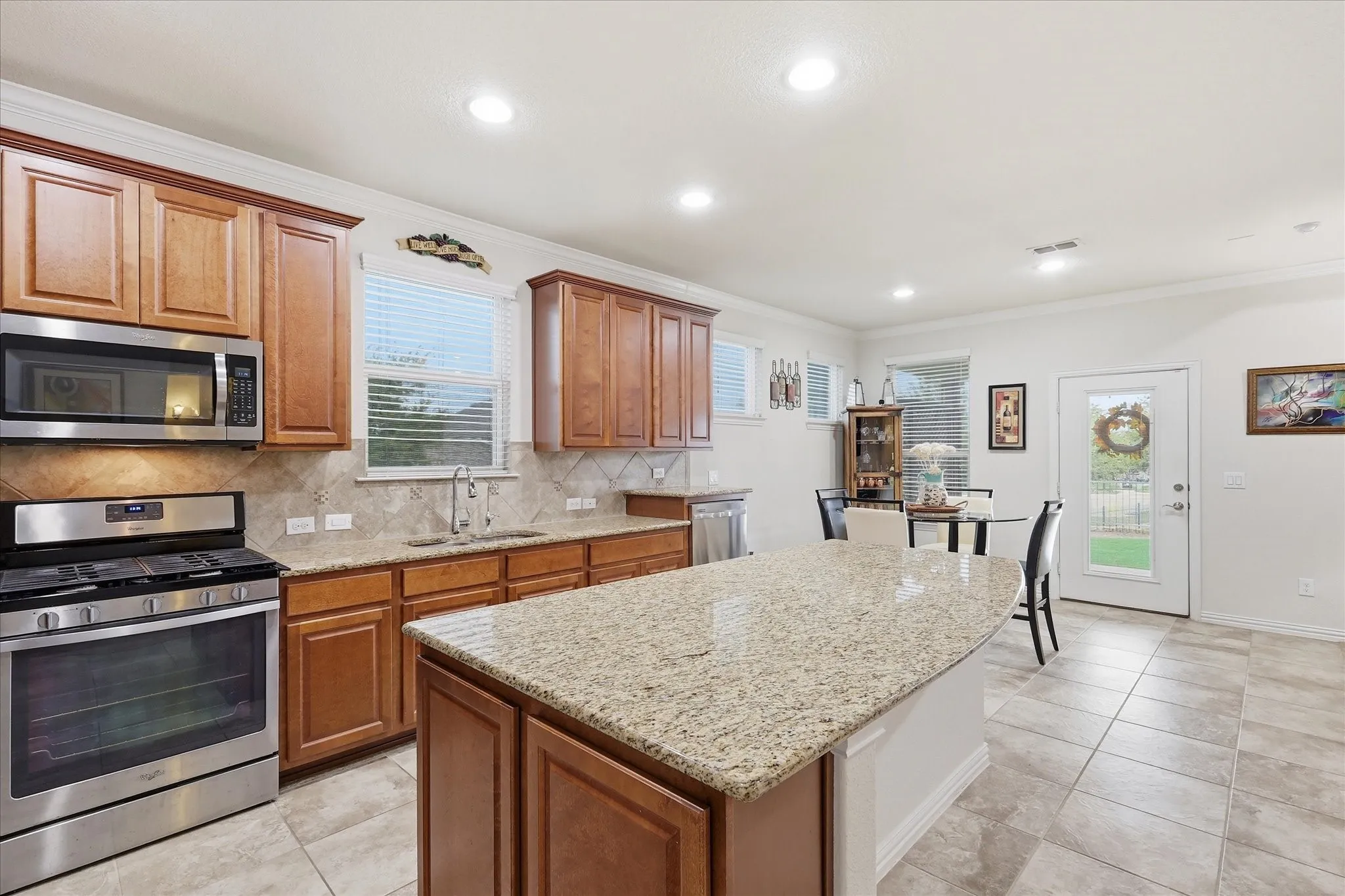 Kitchen featuring wood cabinetry, granite countertops, a central island, tile flooring, and stainless steel appliances