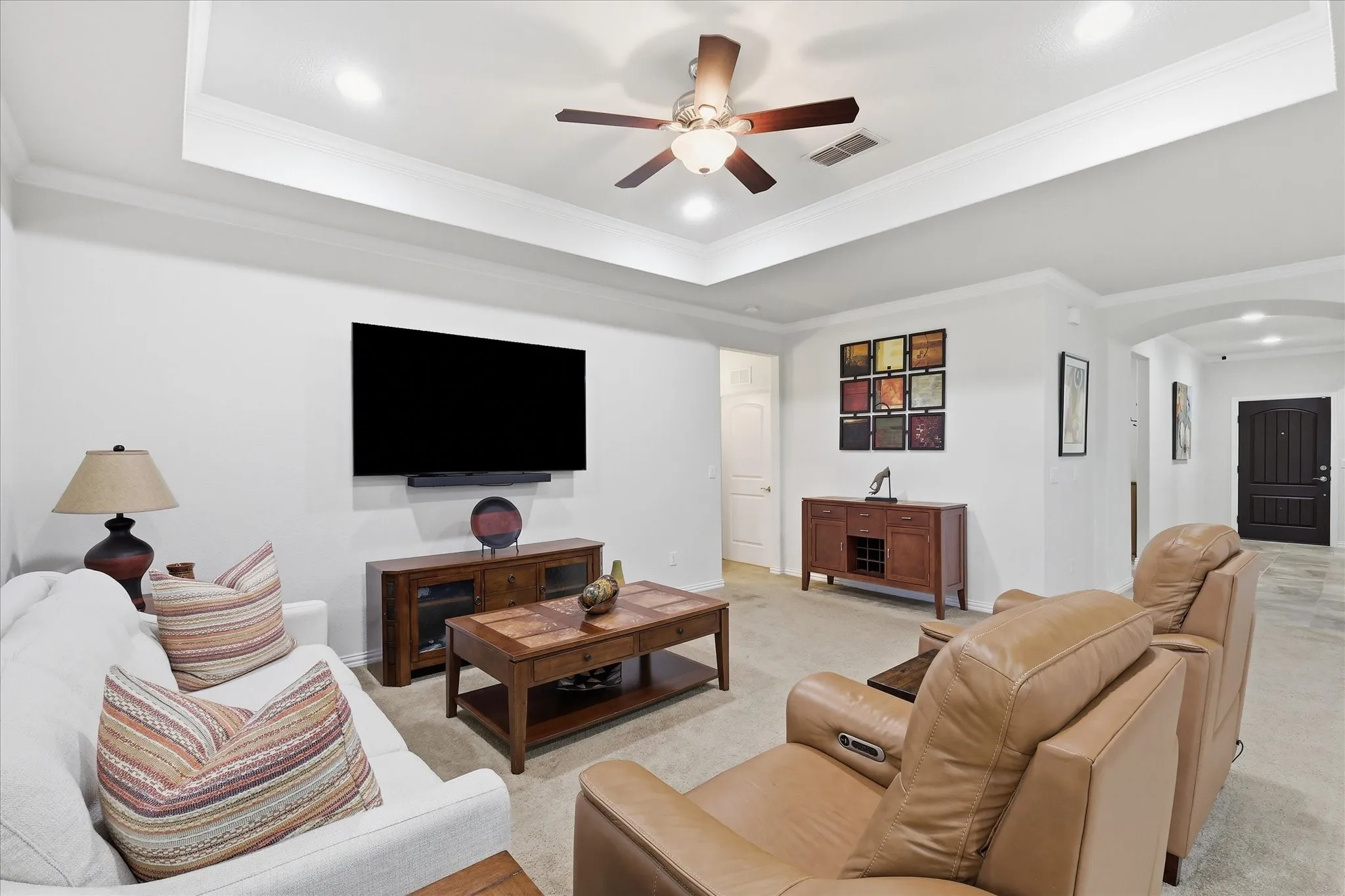 Living area featuring a tray ceiling, recessed lighting, and a ceiling fan with integrated light fixture