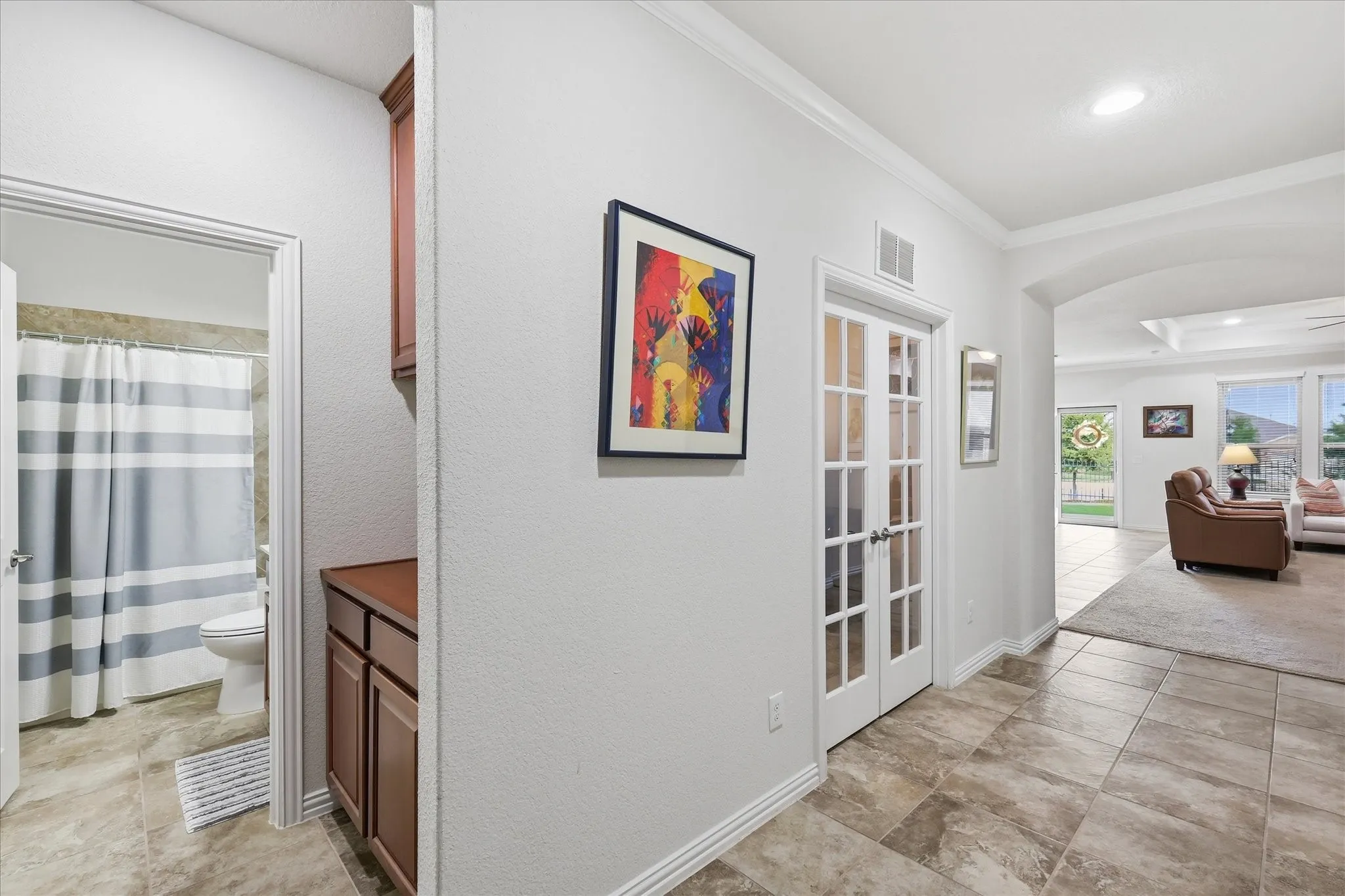 Interior hallway featuring tile flooring, crown molding, built-in cabinetry and French doors to Office