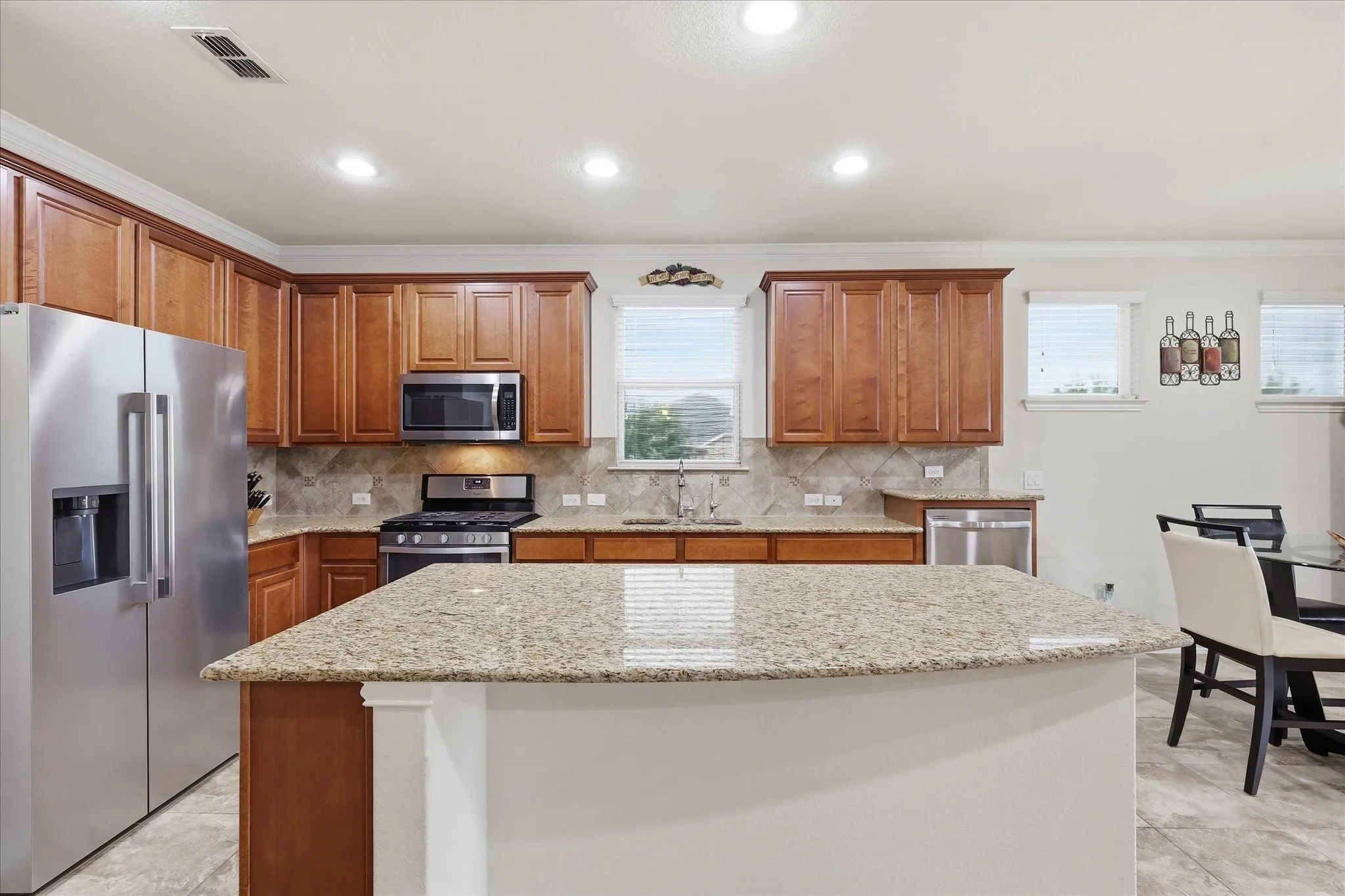 Kitchen featuring granite countertops, an oversized center island, stained wood cabinetry, stainless steel appliances, and a tiled backsplash