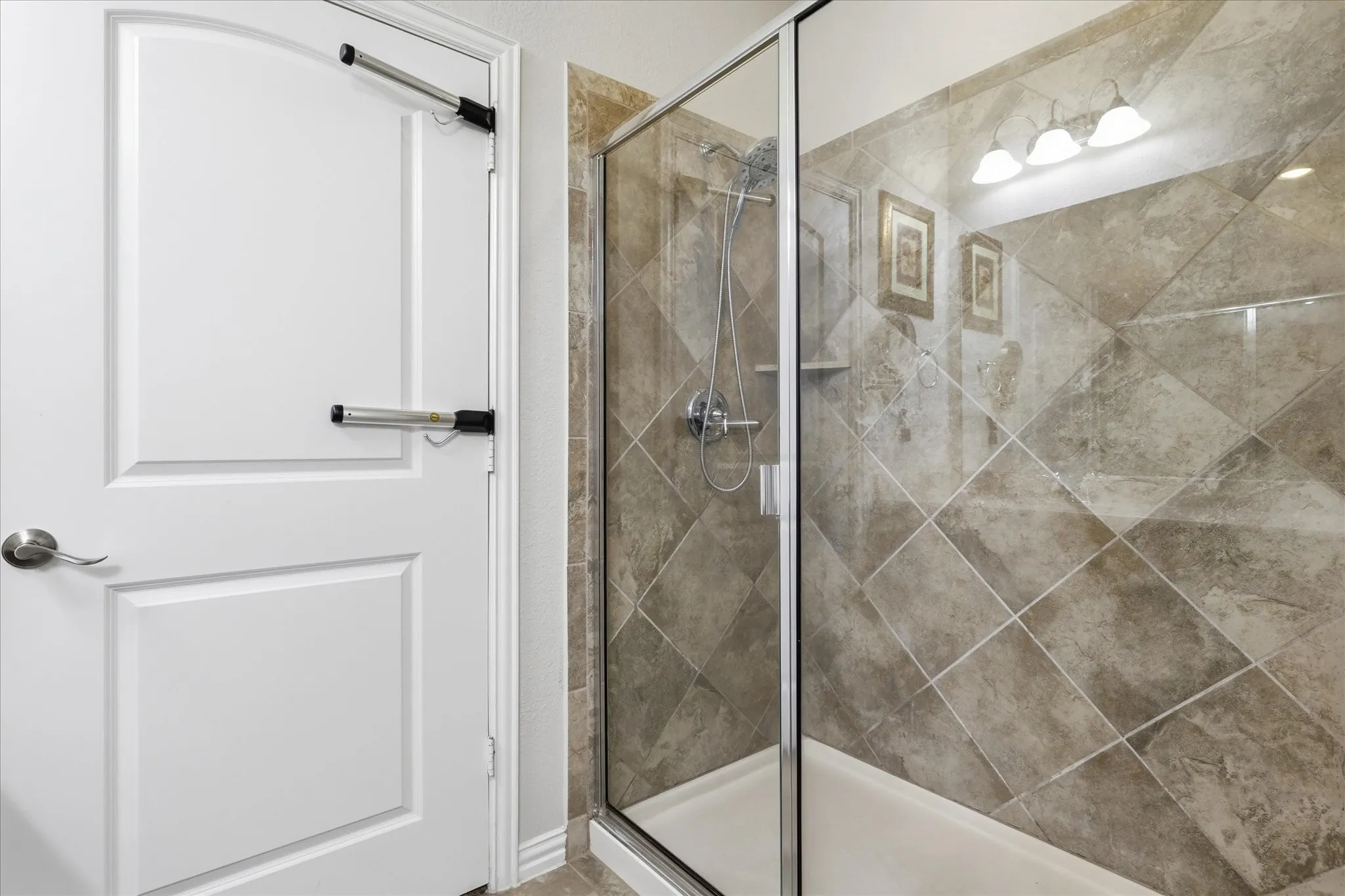 Walk-in shower featuring a glass enclosure, diagonal tile surround, built-in shelving, and a chrome shower fixture