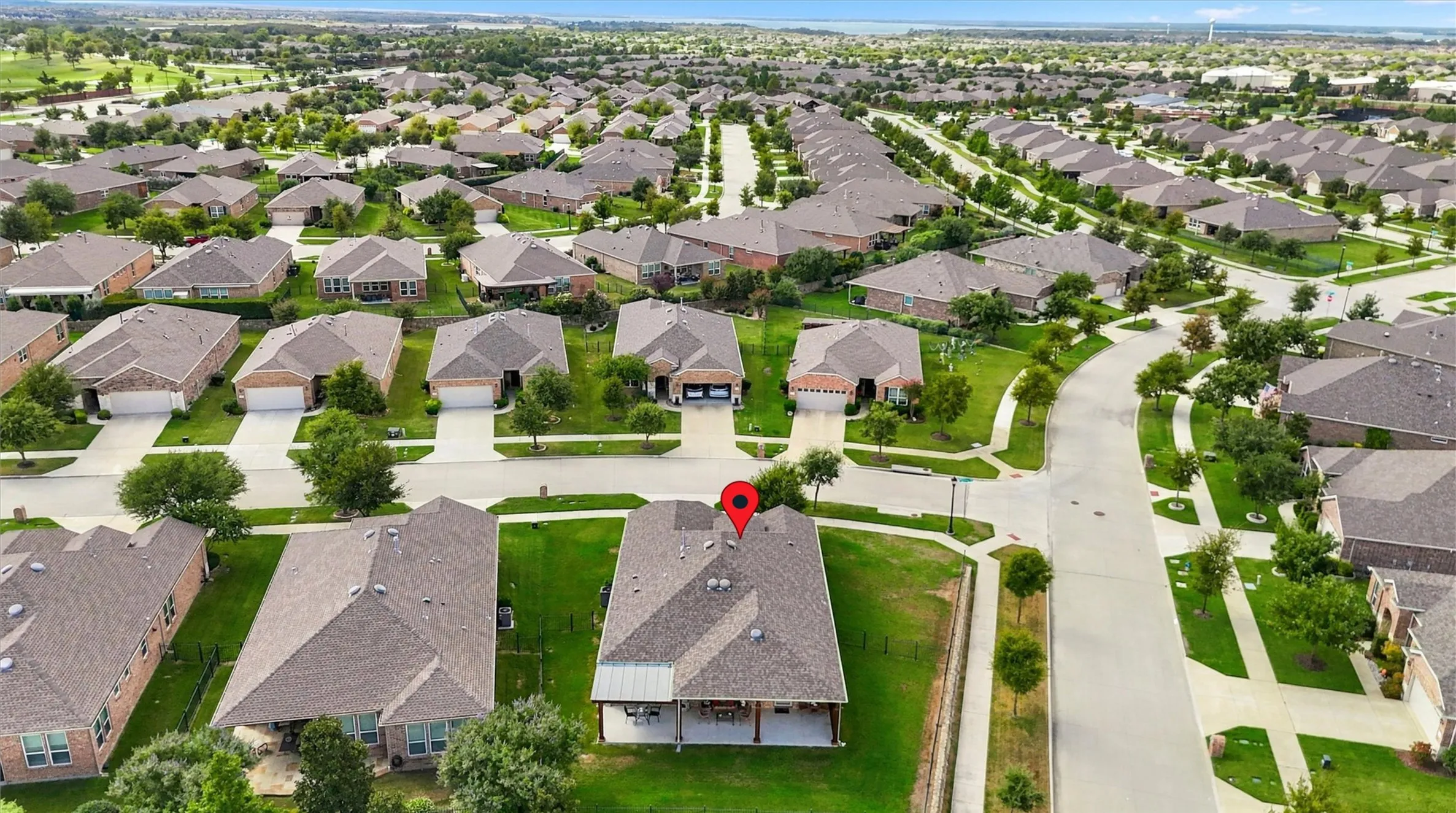 Aerial perspective of a detached single-family residence featuring a shingle roof, integrated two-car garage, and a covered rear patio