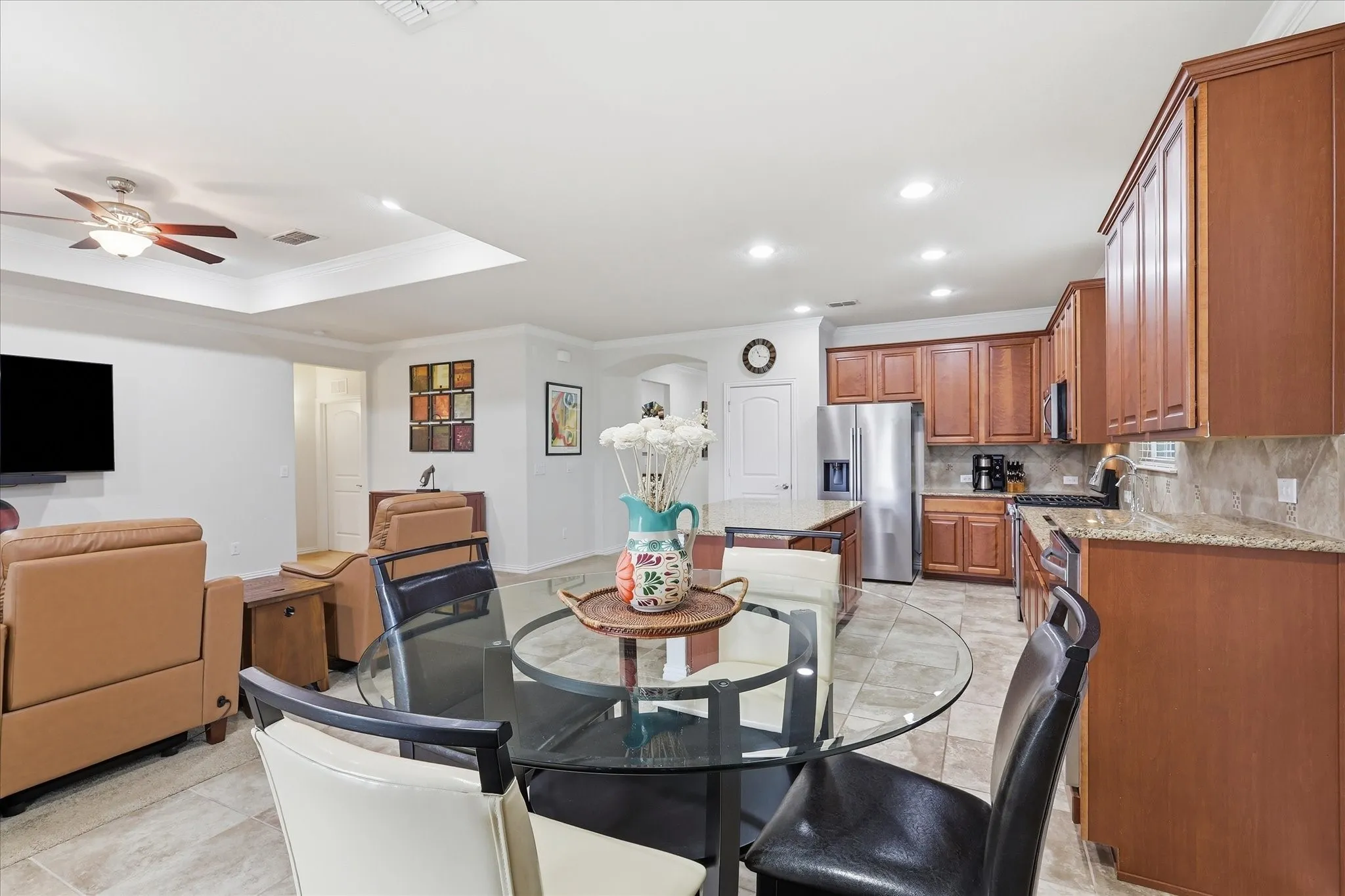 Kitchen featuring wood cabinetry, stone countertops, stone-finish tile flooring, recessed lighting, and a tray ceiling