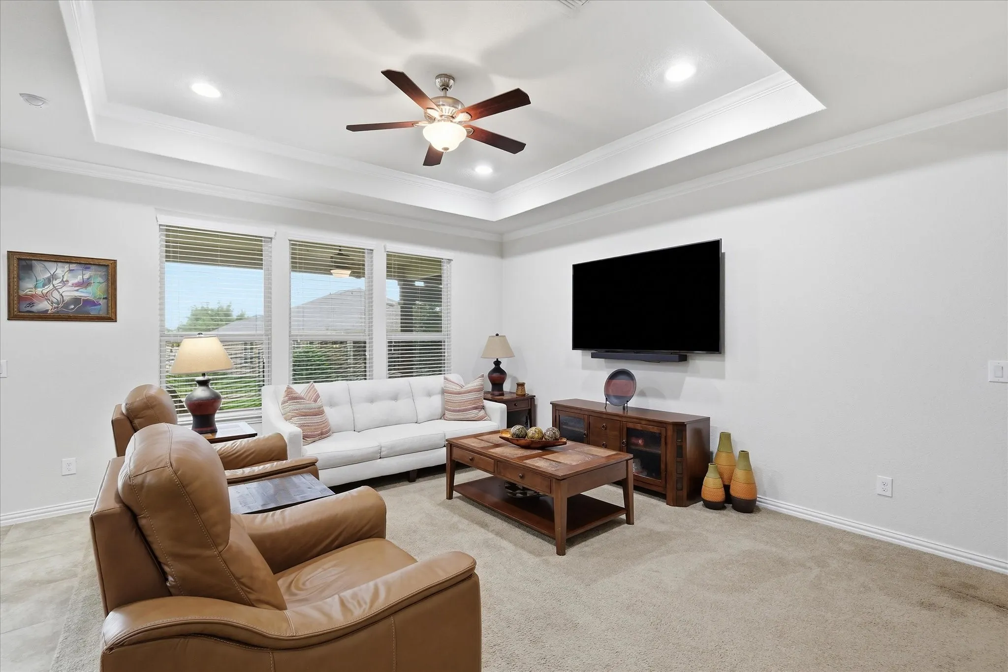 Tray ceiling featuring recessed lighting and a central ceiling fan, expansive windows with blinds, and carpeting