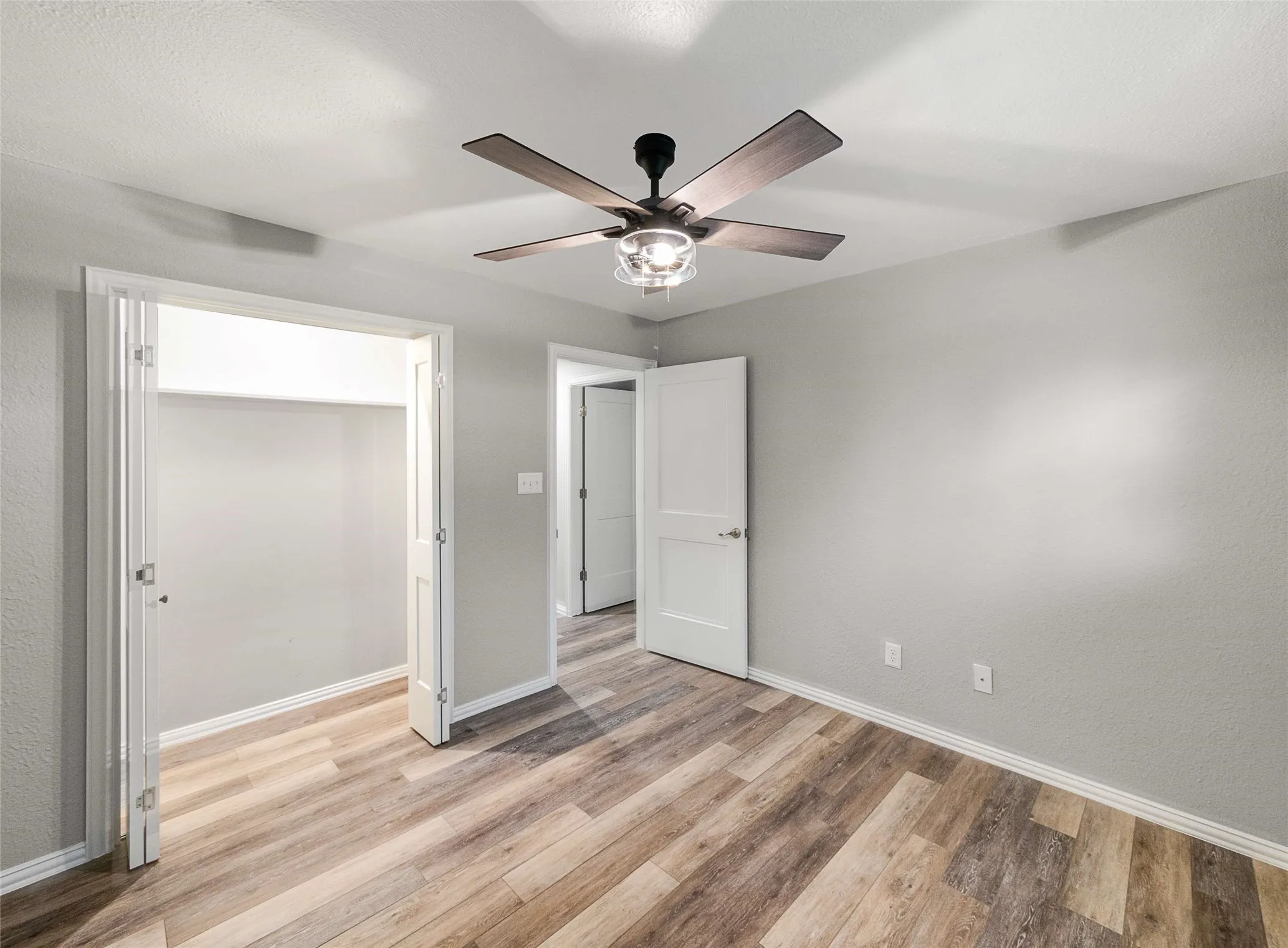 Wood-finish flooring, ceiling fan with integrated light fixture, and two-panel interior doors