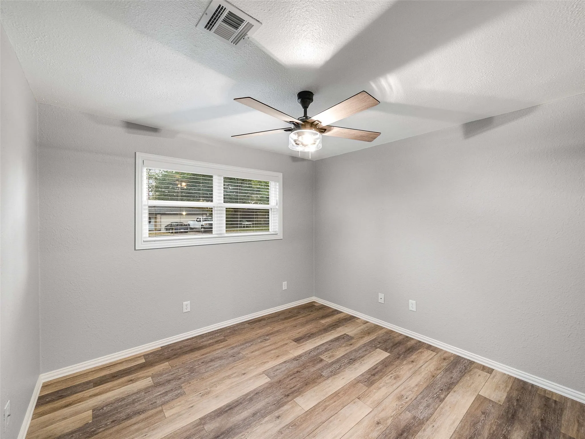 Room featuring wood-finish flooring, neutral wall paint, and a ceiling fan with integrated lighting