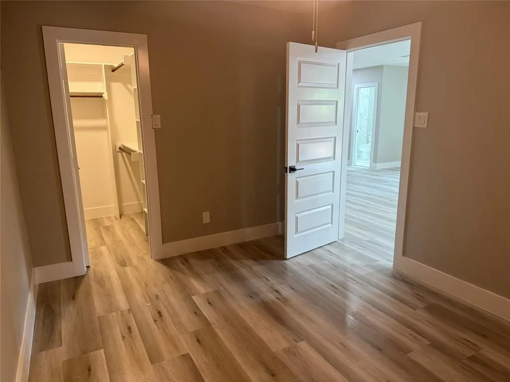 Wood-finish flooring, five-panel interior door with matte black hardware, and built-in closet shelving
