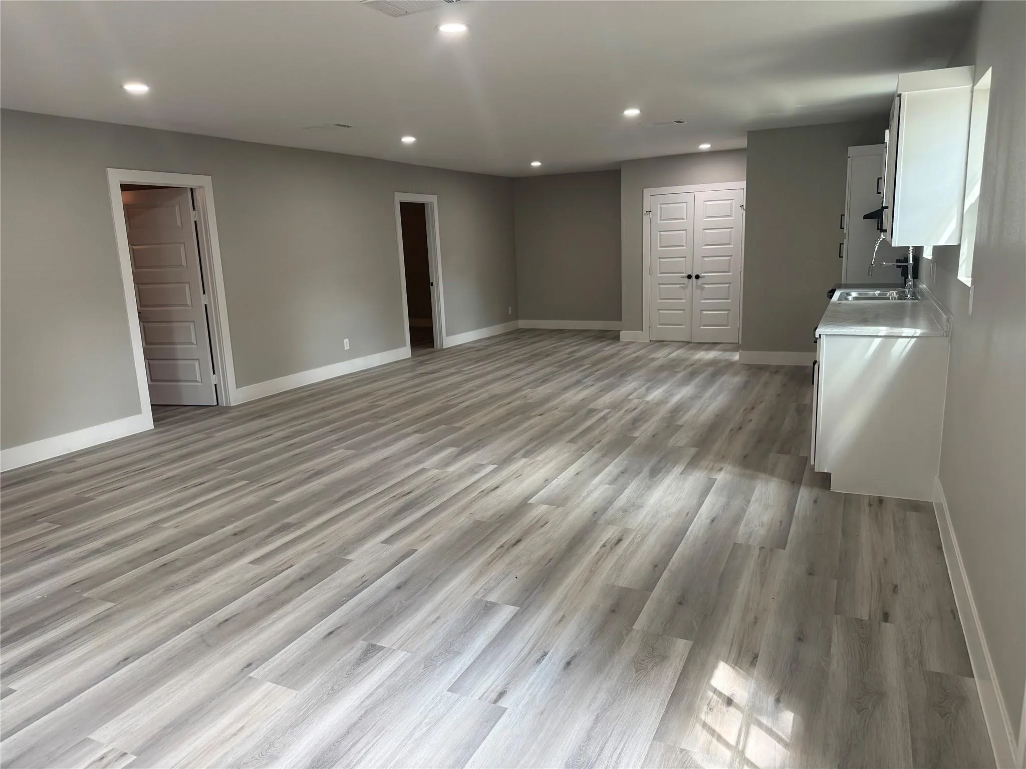 Spacious interior featuring wood-finish flooring, recessed lighting, white cabinetry with countertop, and multi-panel doors