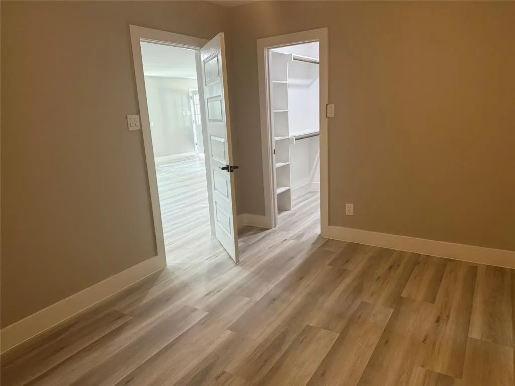 Wood-finish flooring throughout, multi-panel interior doors, and custom built-in shelving within the closet area