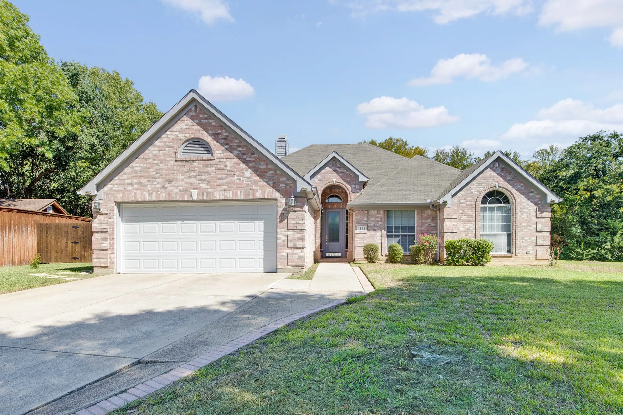 Brick exterior featuring a multi-gabled roofline, an arched entryway, stone quoins, and a two-car garage