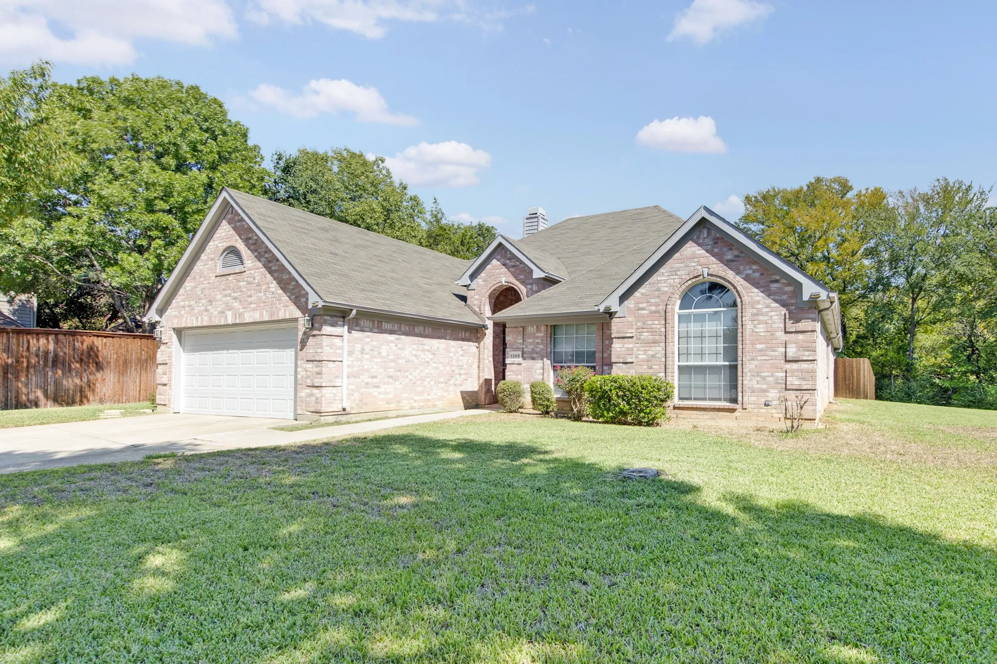 Brick exterior, front-facing two-car garage, arched entryway, and multi-gabled roofline