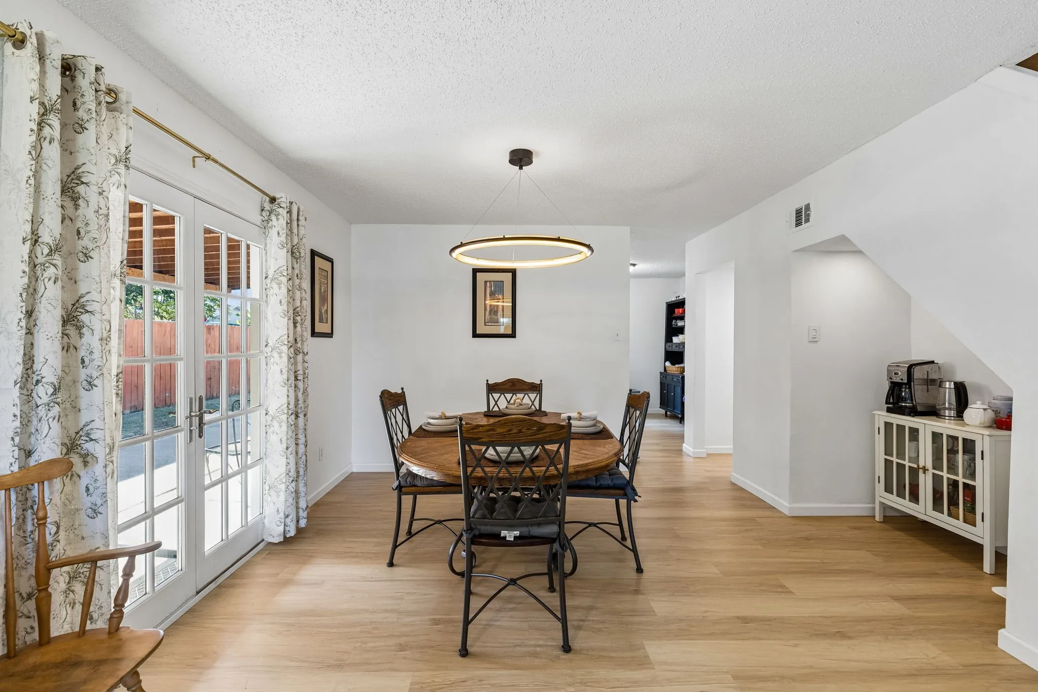 Dining area featuring wood-finish flooring, a modern circular LED pendant light, and double glass-paned doors