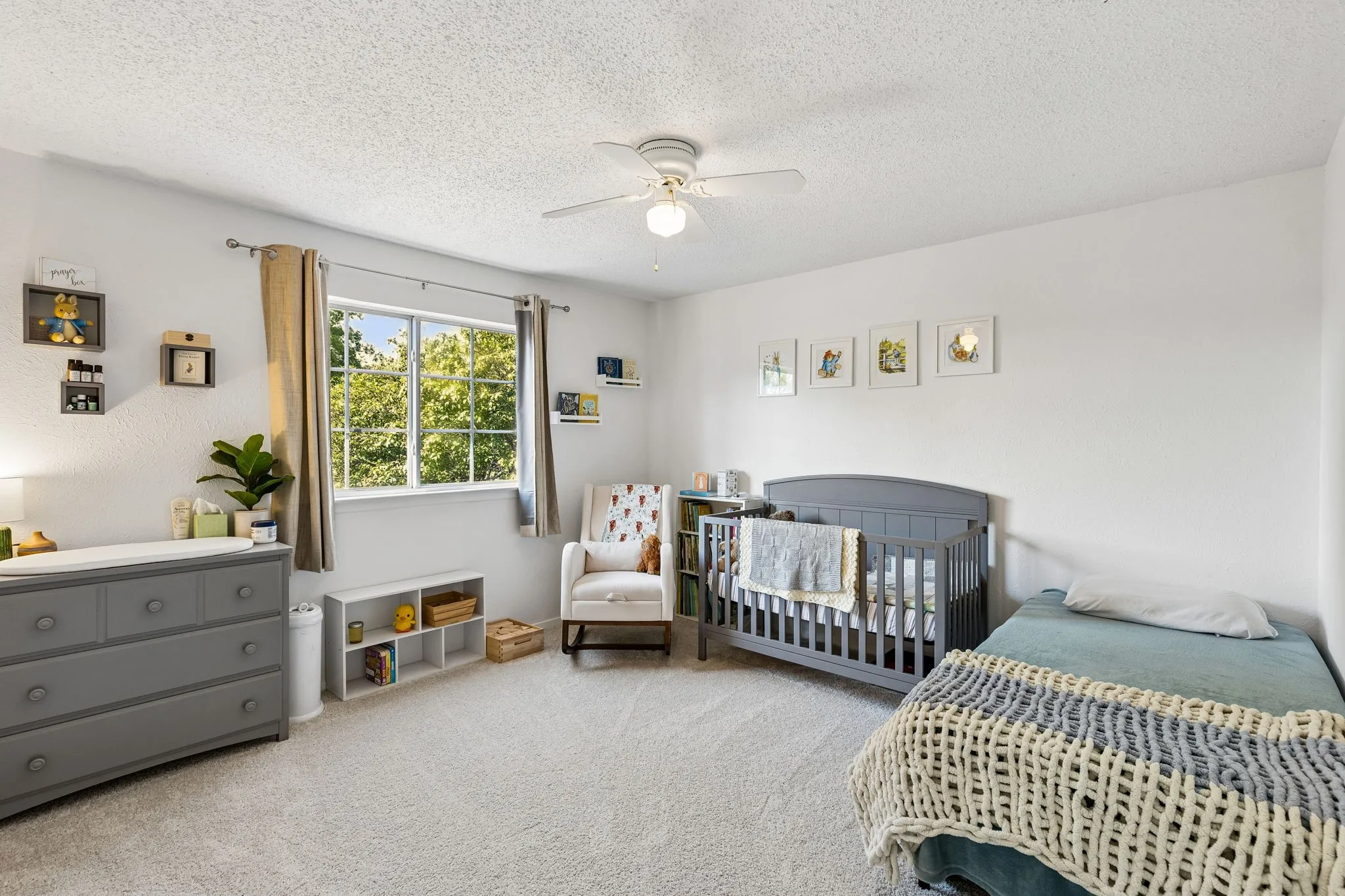 Neutral wall-to-wall carpeting, ceiling fan with integrated lighting, and a large window with window hardware