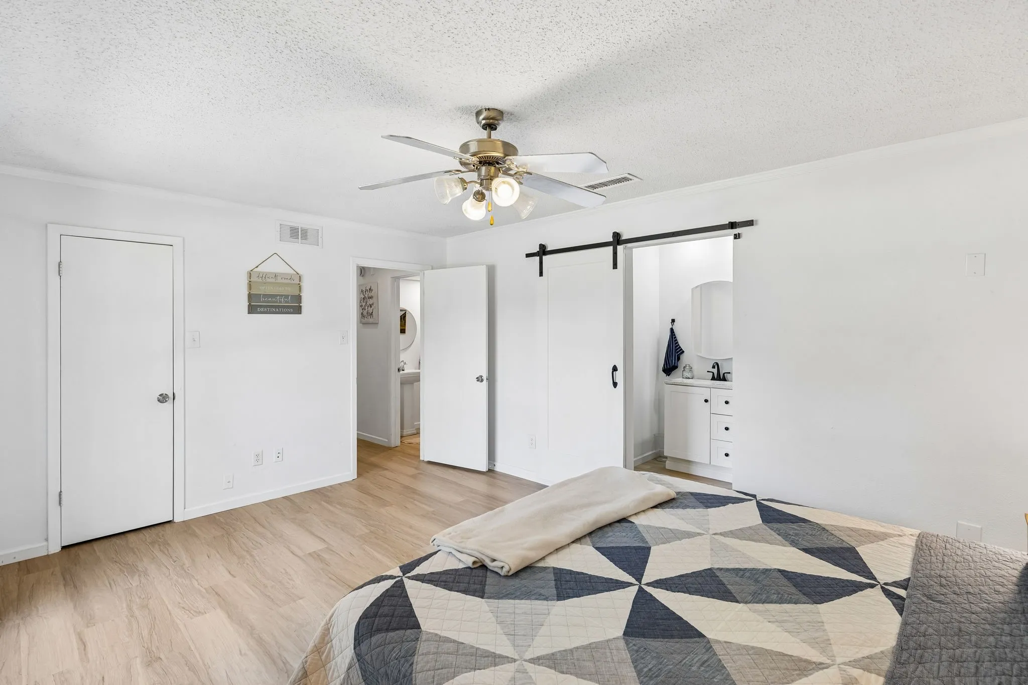 Interior featuring wood-finish flooring, a ceiling fan with integrated lighting, and a sliding barn door with black hardware