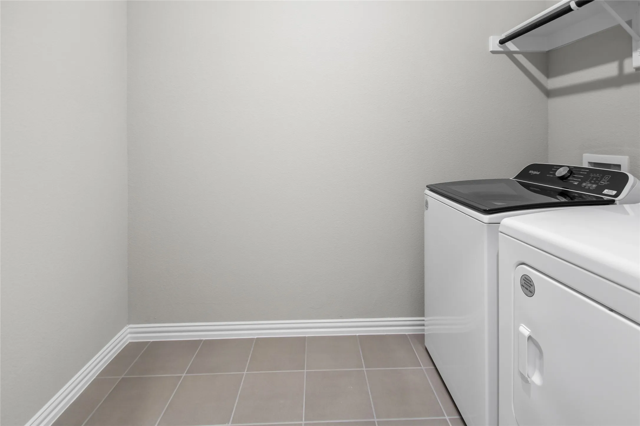 Utility room featuring neutral-toned tile flooring and wall-mounted storage shelving