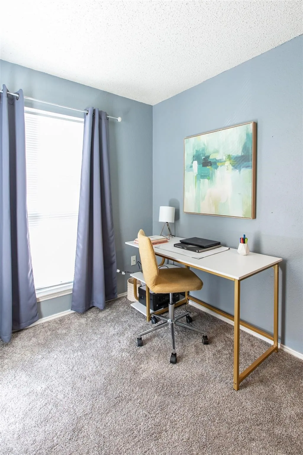 Room featuring neutral wall-to-wall carpeting, blue-toned paint, and a large window with a horizontal blind