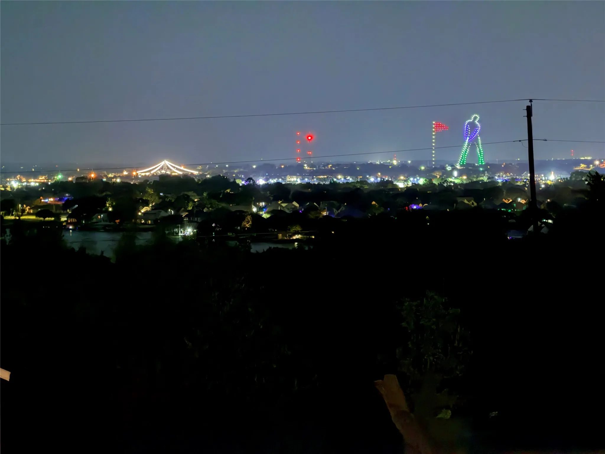 Elevated perspective featuring city lights, distant illuminated structures, and water