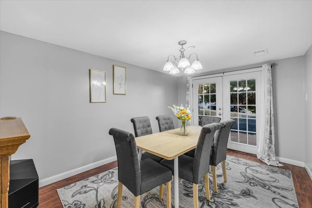 Dining area featuring wood-finish flooring, a multi-light chandelier, and glass-paned French doors