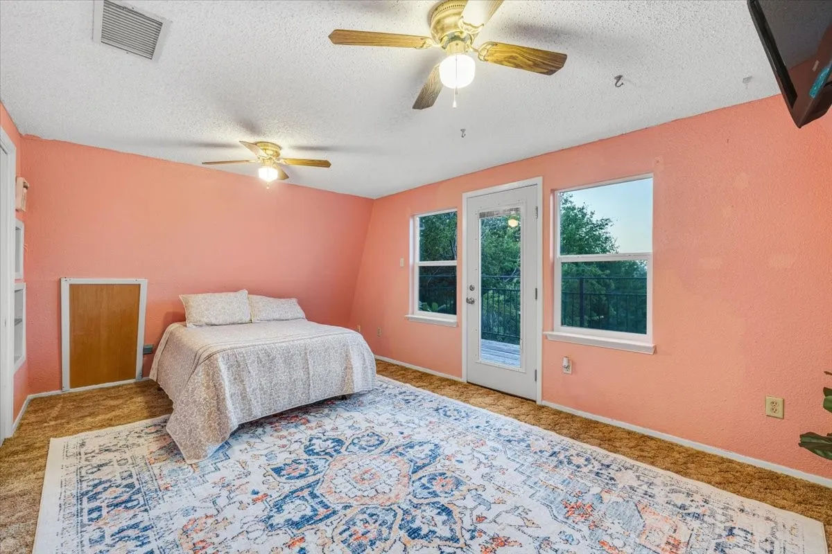 Interior room featuring dual ceiling fans, two large windows, a glass-paneled exterior door, and built-in storage cabinet