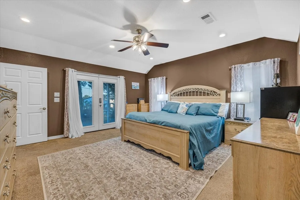 Vaulted ceiling with integrated recessed lighting, central ceiling fan, and double glass-paned doors