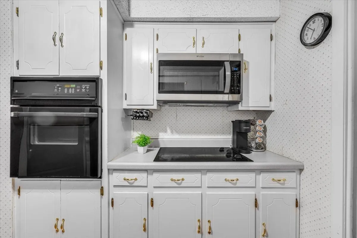Kitchen featuring white cabinetry with gold-tone hardware, built-in wall oven, integrated stovetop, and over-the-range microwave