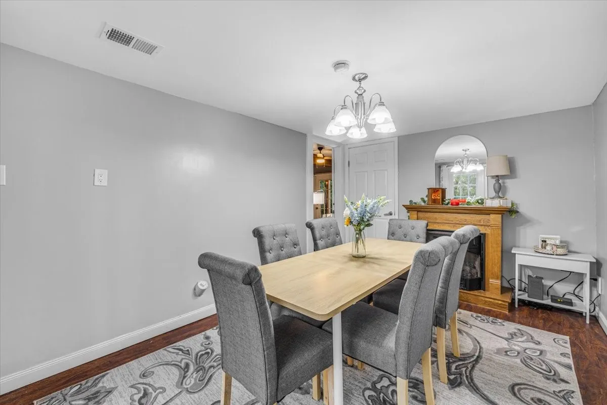 Dining area featuring a wood-finish fireplace mantel, a multi-light chandelier, and dark wood-finish flooring
