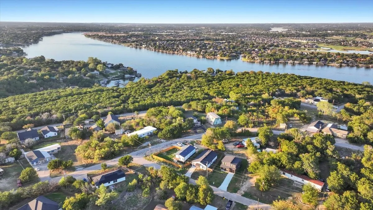 Aerial perspective featuring expansive waterfront positioning, mature tree canopy, and established neighborhood topography