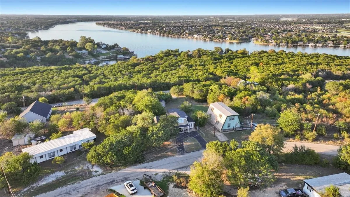 Aerial perspective featuring significant mature tree coverage, expansive waterfront surroundings, and varied topography