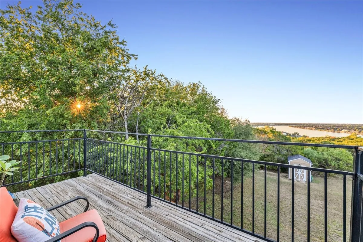 Elevated wood-plank deck featuring a black metal railing and expansive water scenery