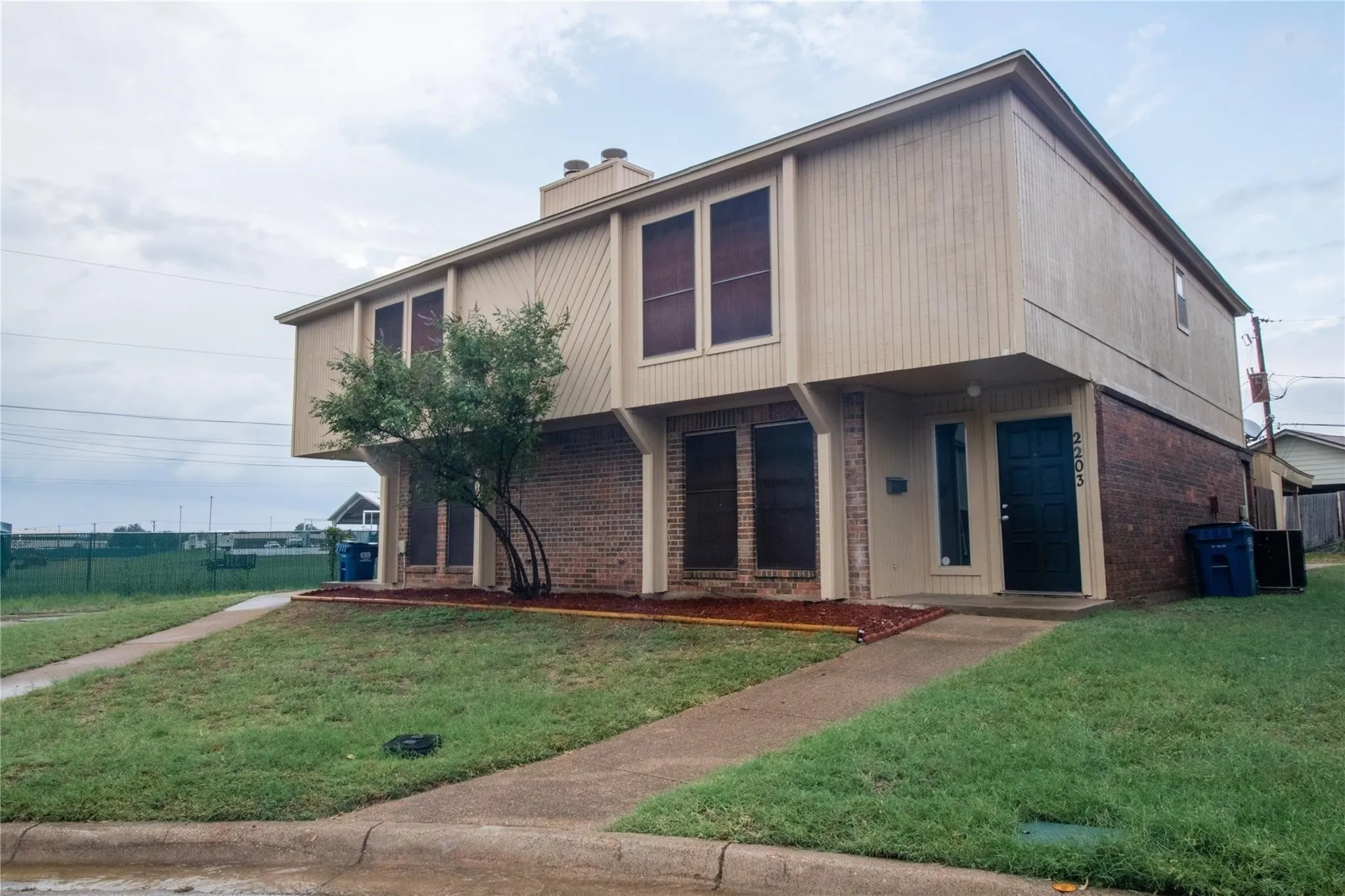 Two-story exterior featuring a brick and vertical wood-finish siding facade, masonry chimney, and concrete walkways