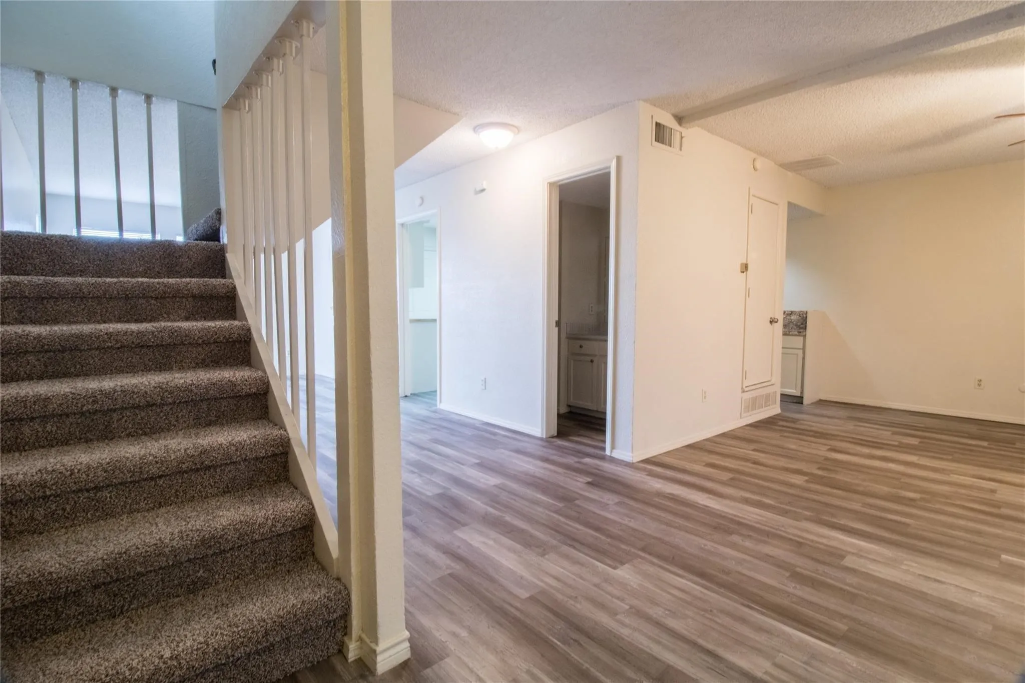 Interior featuring wood-finish flooring, staircase with a white balustrade, and recessed ceiling lighting