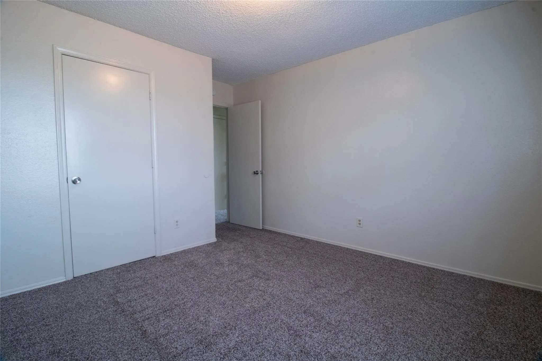Neutral-toned wall finish, textured ceiling, and neutral carpeting