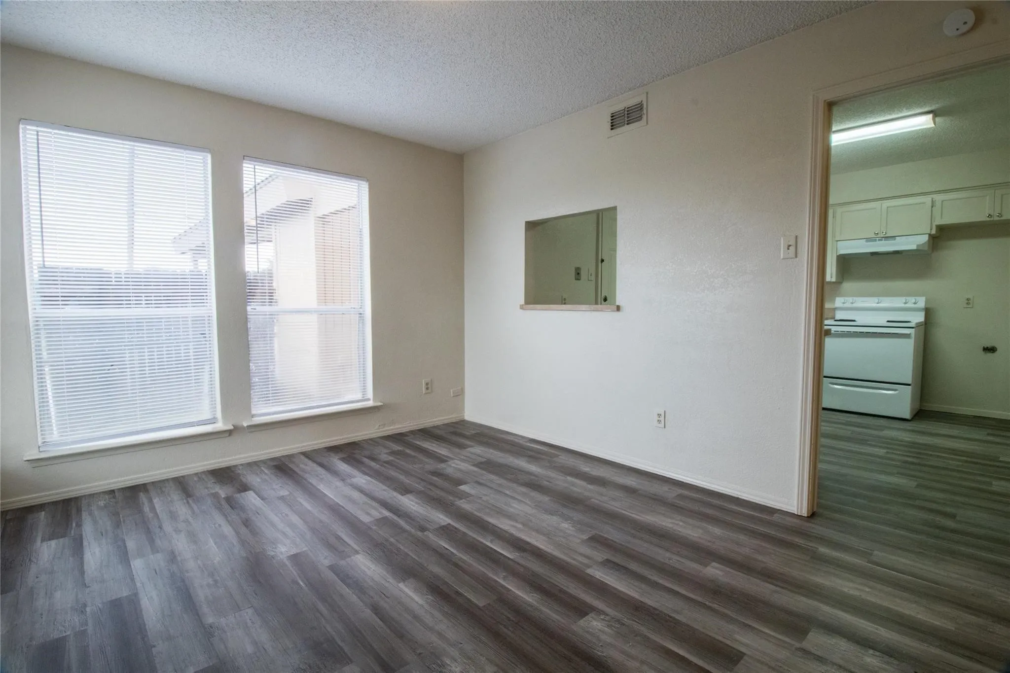 Wood-finish flooring, dual windows with integrated blinds, and an interior wall cutout