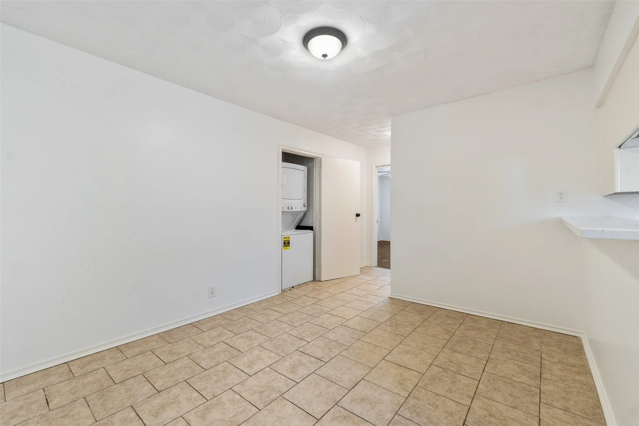 Tile flooring, white walls, and a dedicated closet housing a stacked washer and dryer