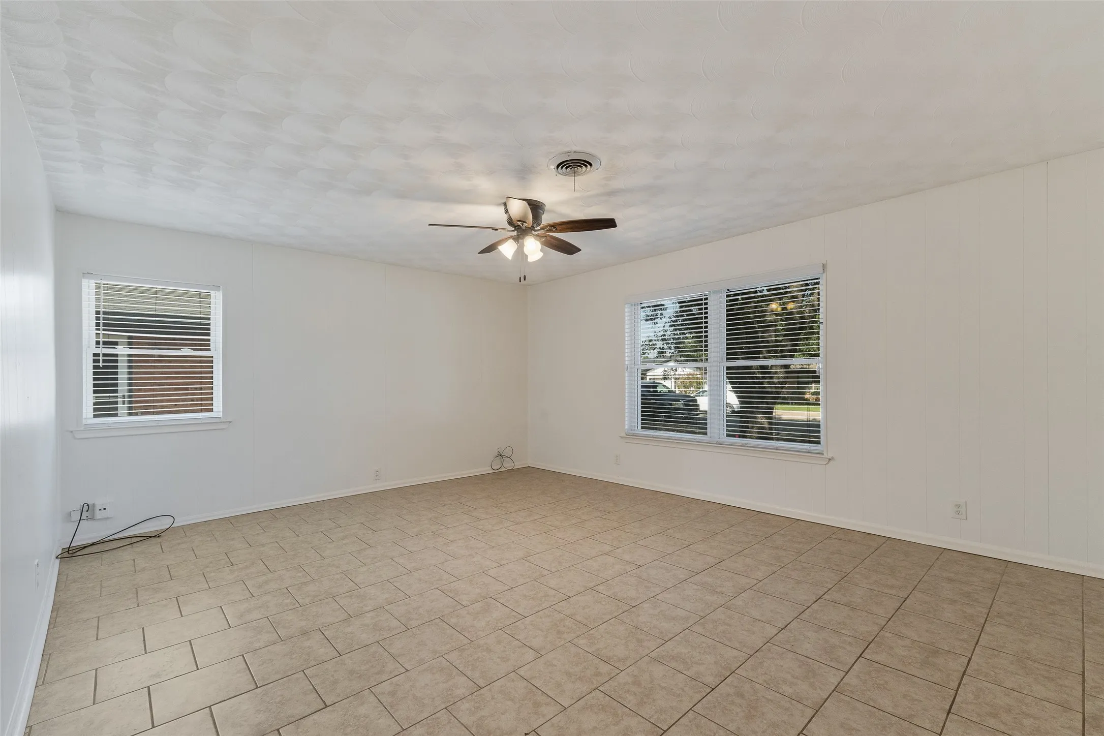 Neutral-toned ceramic tile flooring, multi-light ceiling fan, and large windows with horizontal blinds