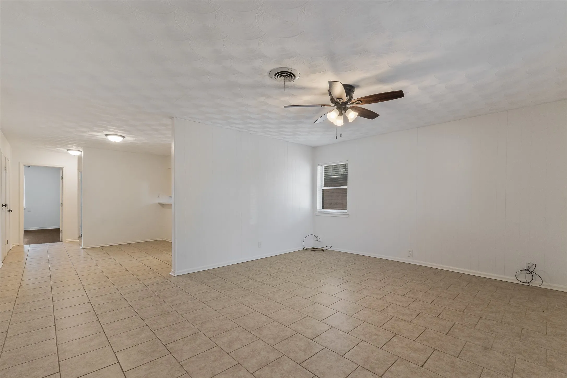 Interior space featuring tile flooring, ceiling fan with integrated lighting, and textured ceiling finish