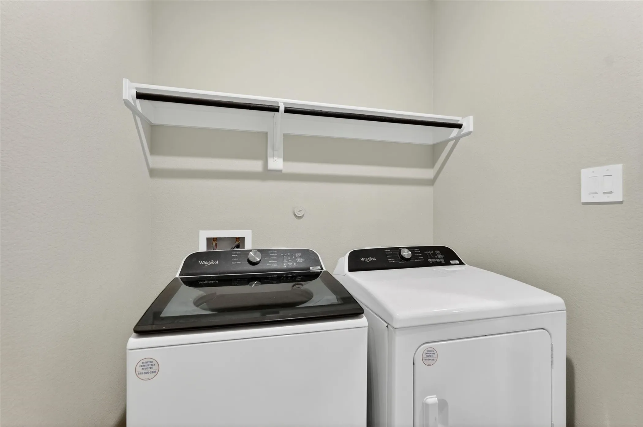 Dedicated laundry area featuring a white wall-mounted shelf with an integrated hanging rod