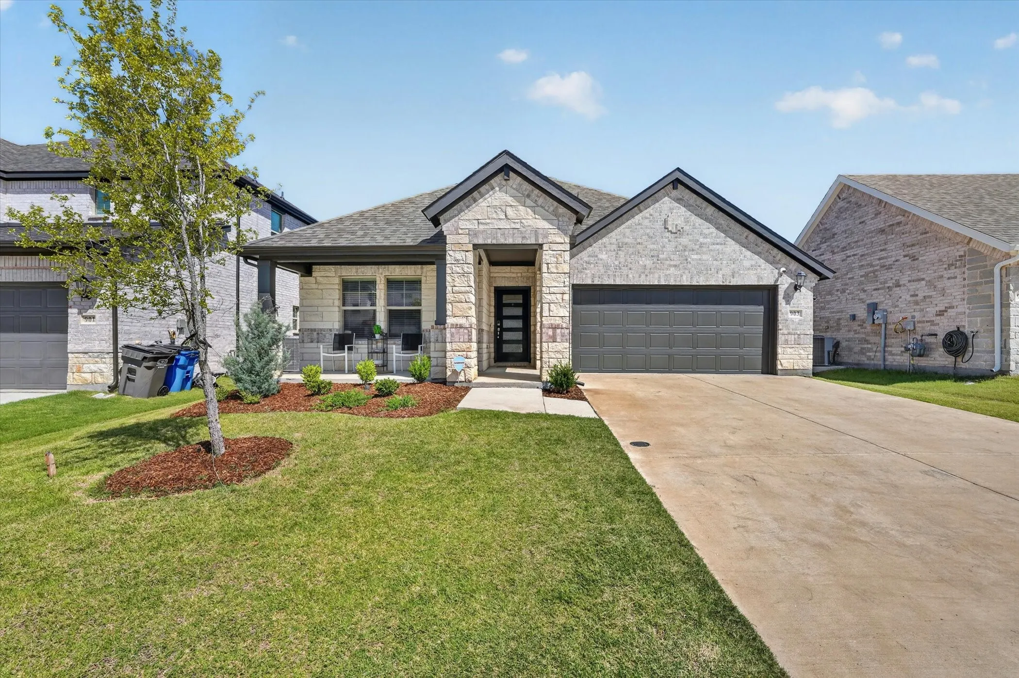 Contemporary single-story residence featuring a stone and brick exterior with dark trim