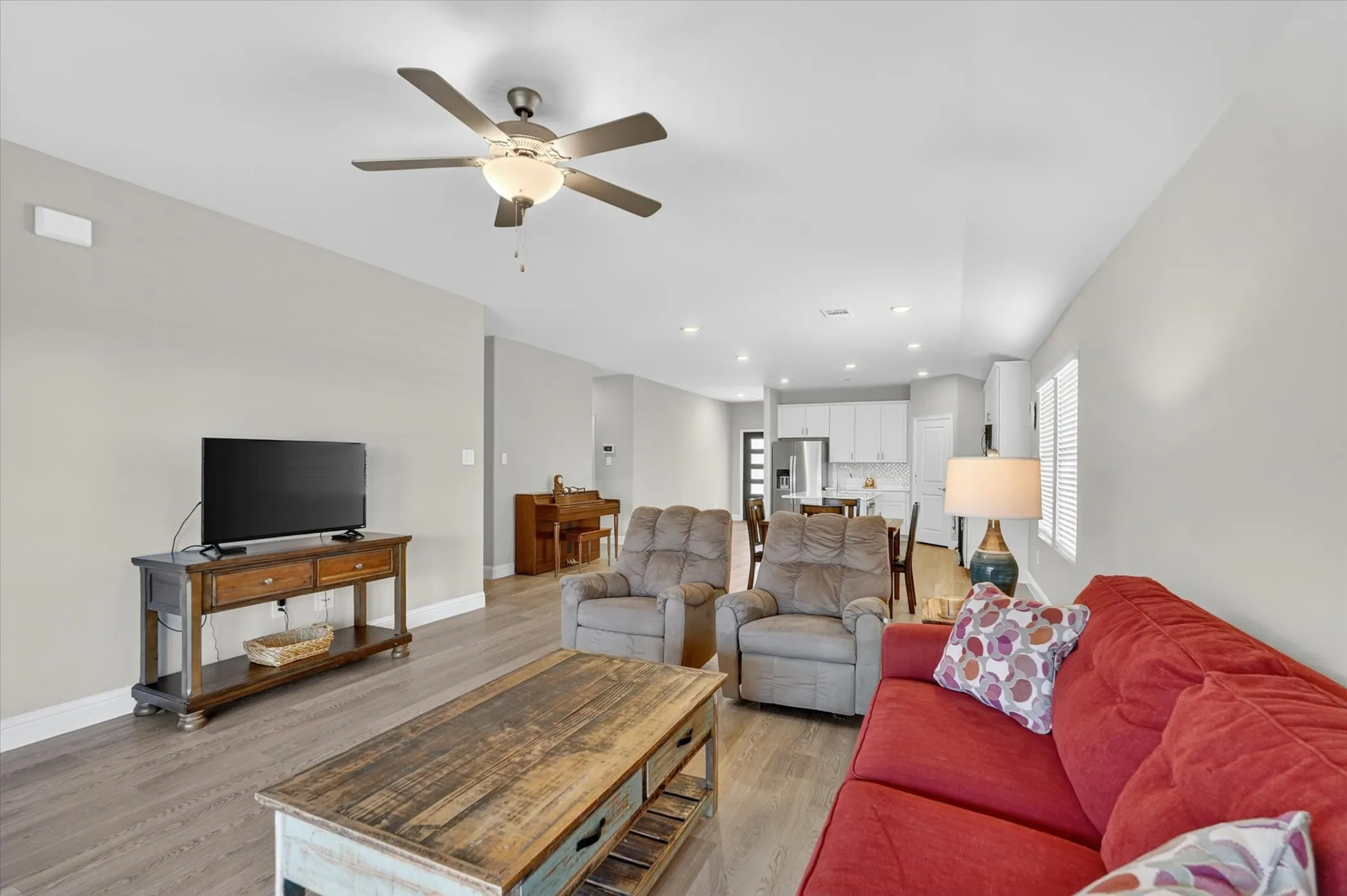 Open-concept living area featuring wood-finish flooring, recessed lighting, and a ceiling fan with integrated lighting