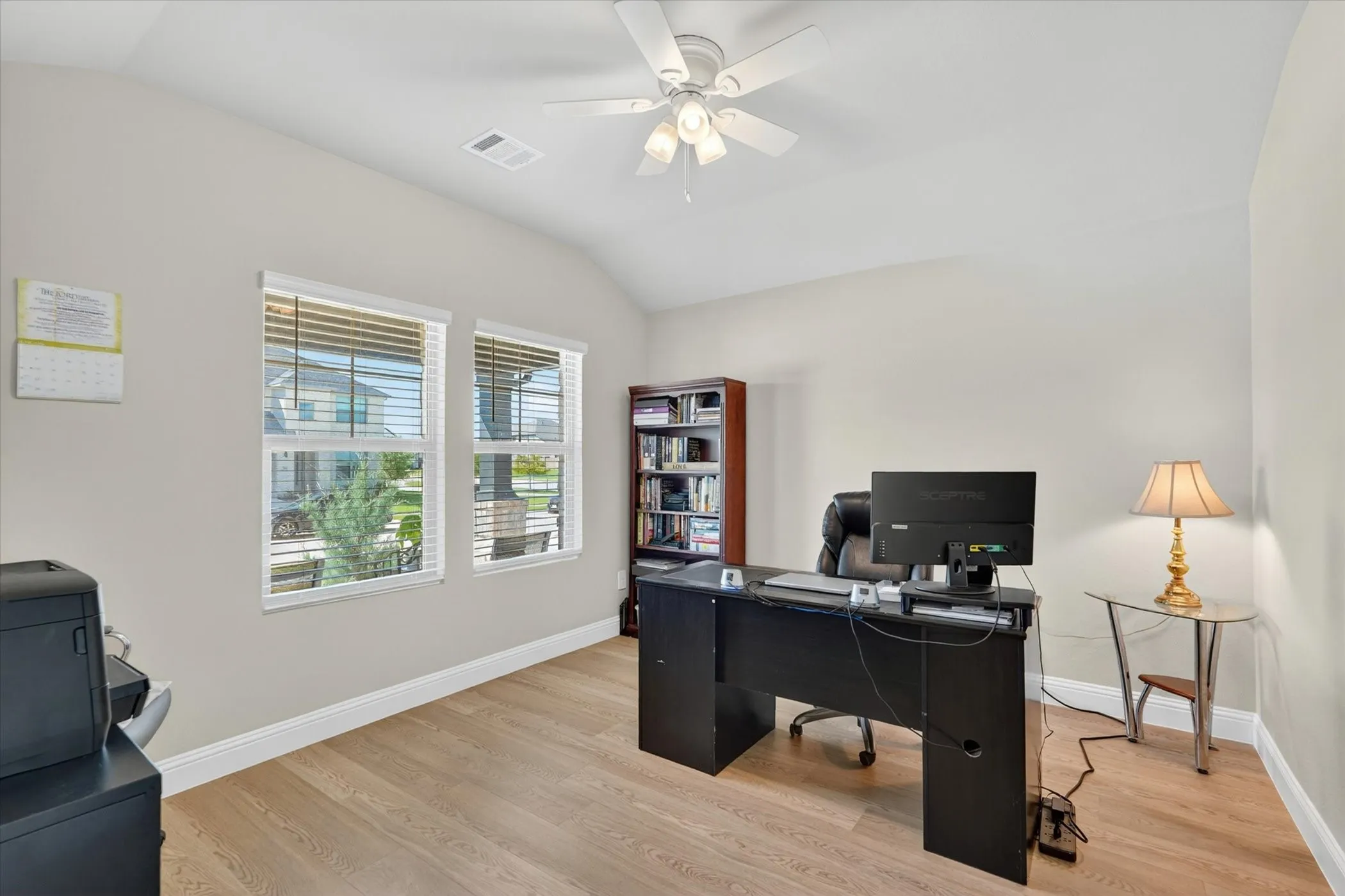 Spacious room featuring wood-finish flooring, vaulted ceilings, and a ceiling fan with integrated lighting