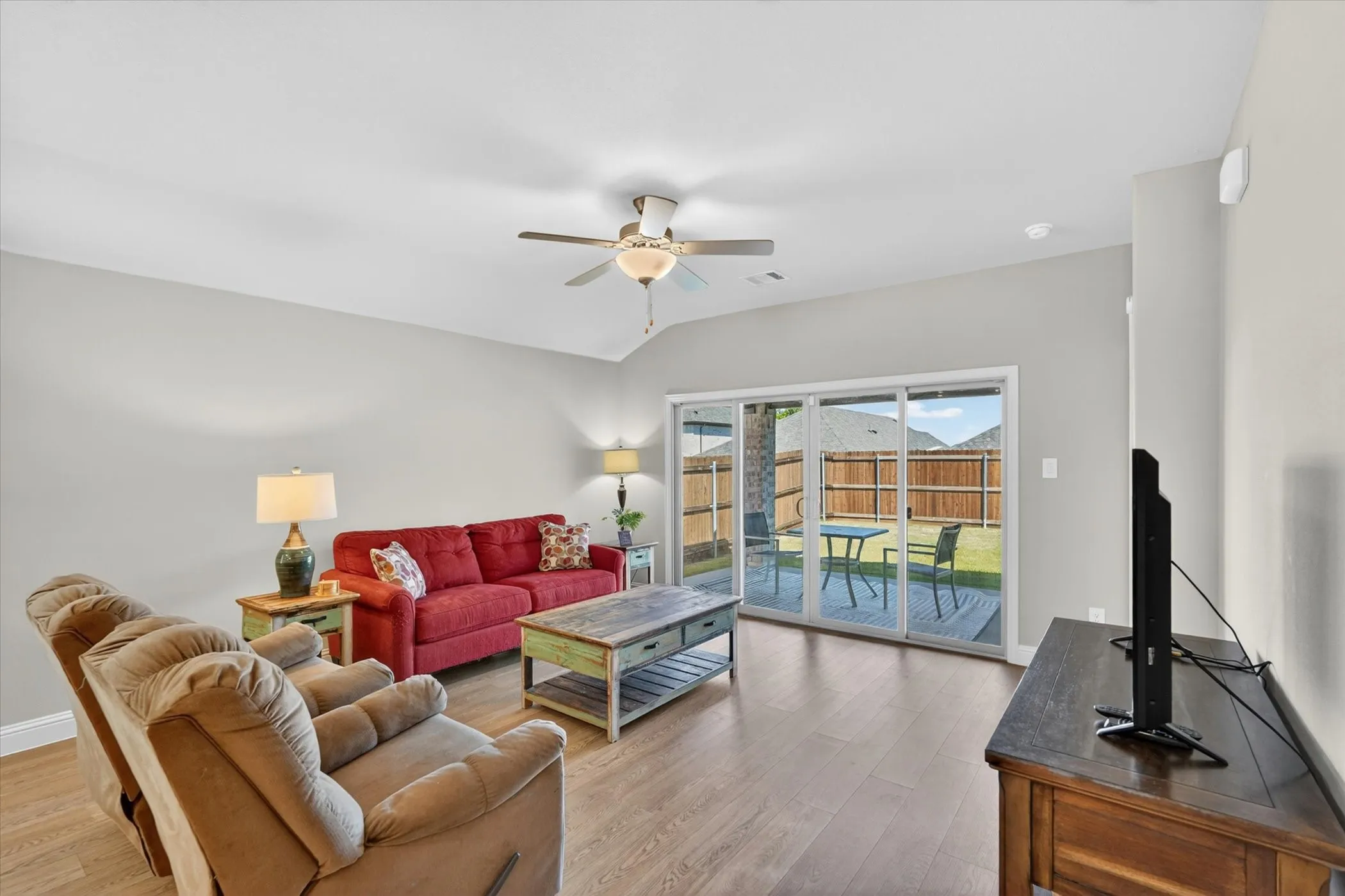 Open concept living area featuring wood-finish flooring, light gray walls, and a vaulted ceiling with a ceiling fan