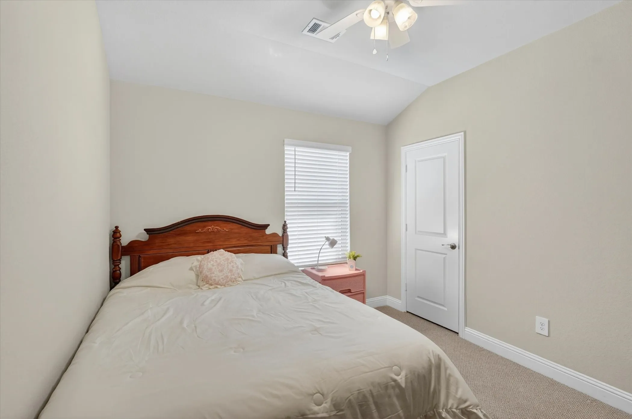 Carpeted room featuring a vaulted ceiling and a ceiling fan with integrated lighting