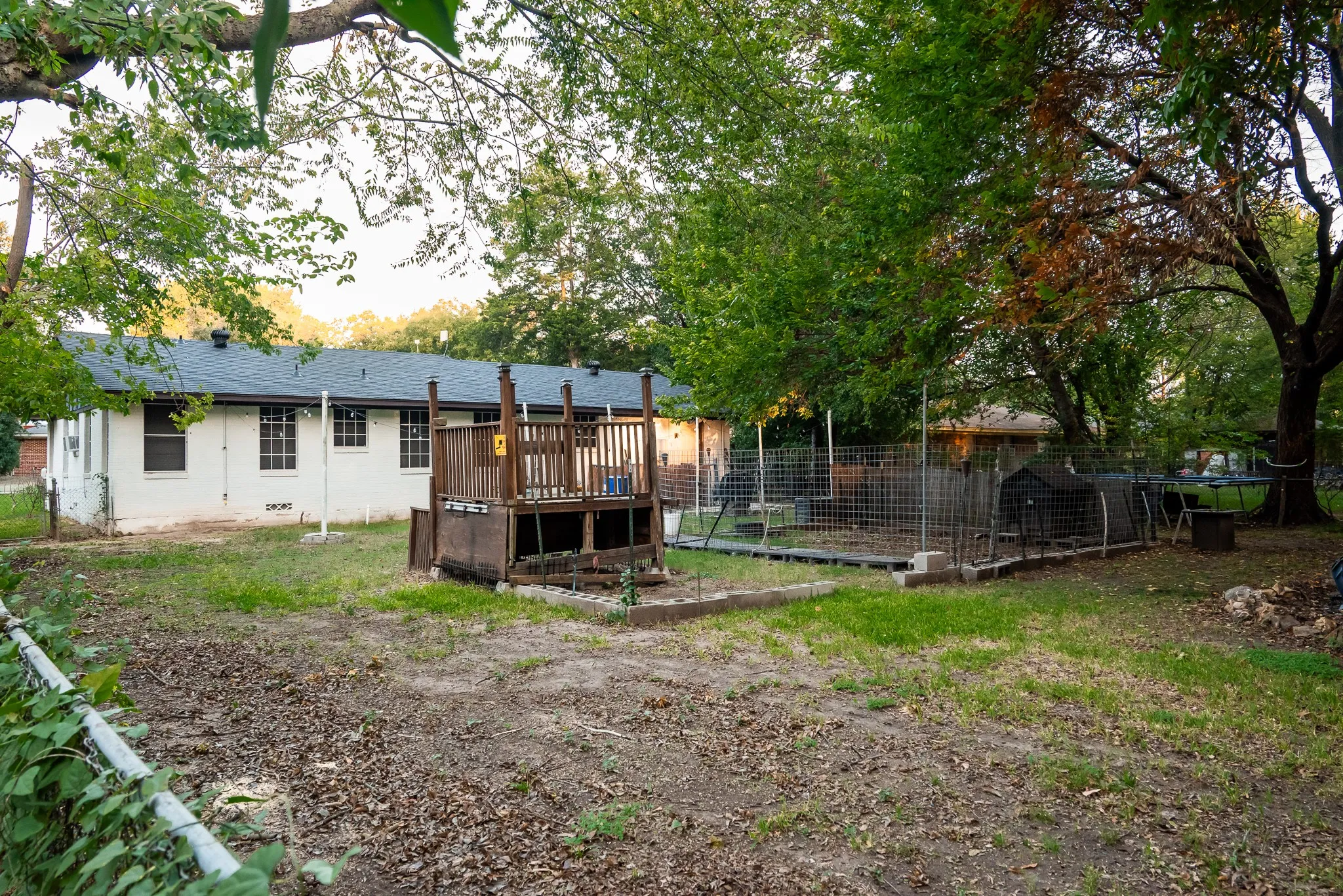 Spacious backyard featuring a wood deck, perimeter wire fencing, and mature trees