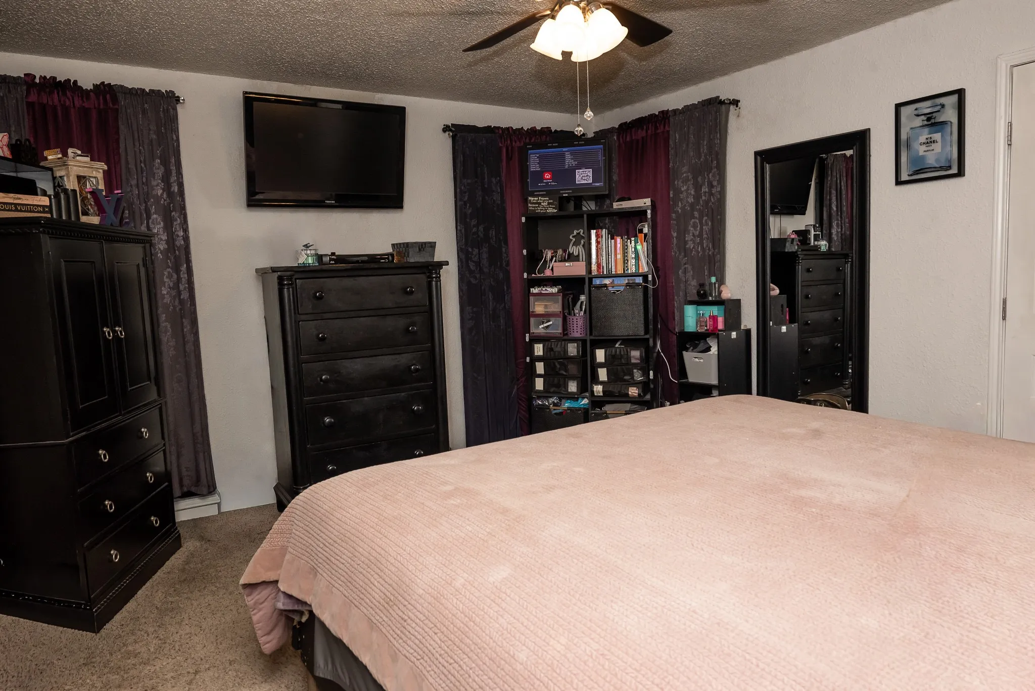 Bedroom featuring neutral-toned carpeting, a multi-blade ceiling fan with integrated lighting, and a solid-core entry door