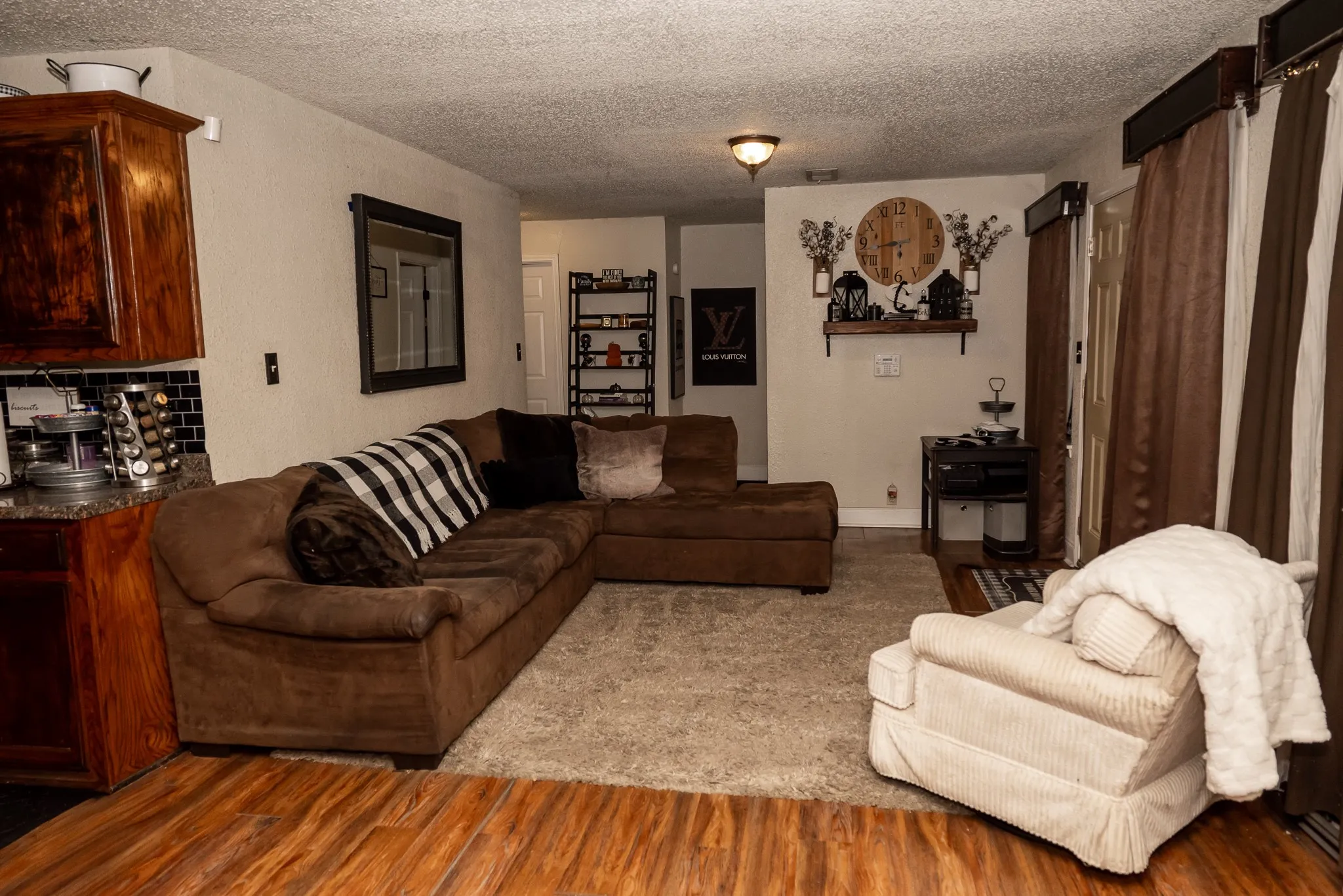 Living area featuring wood-finish flooring, carpeted flooring, and wood cabinetry with a tile backsplash