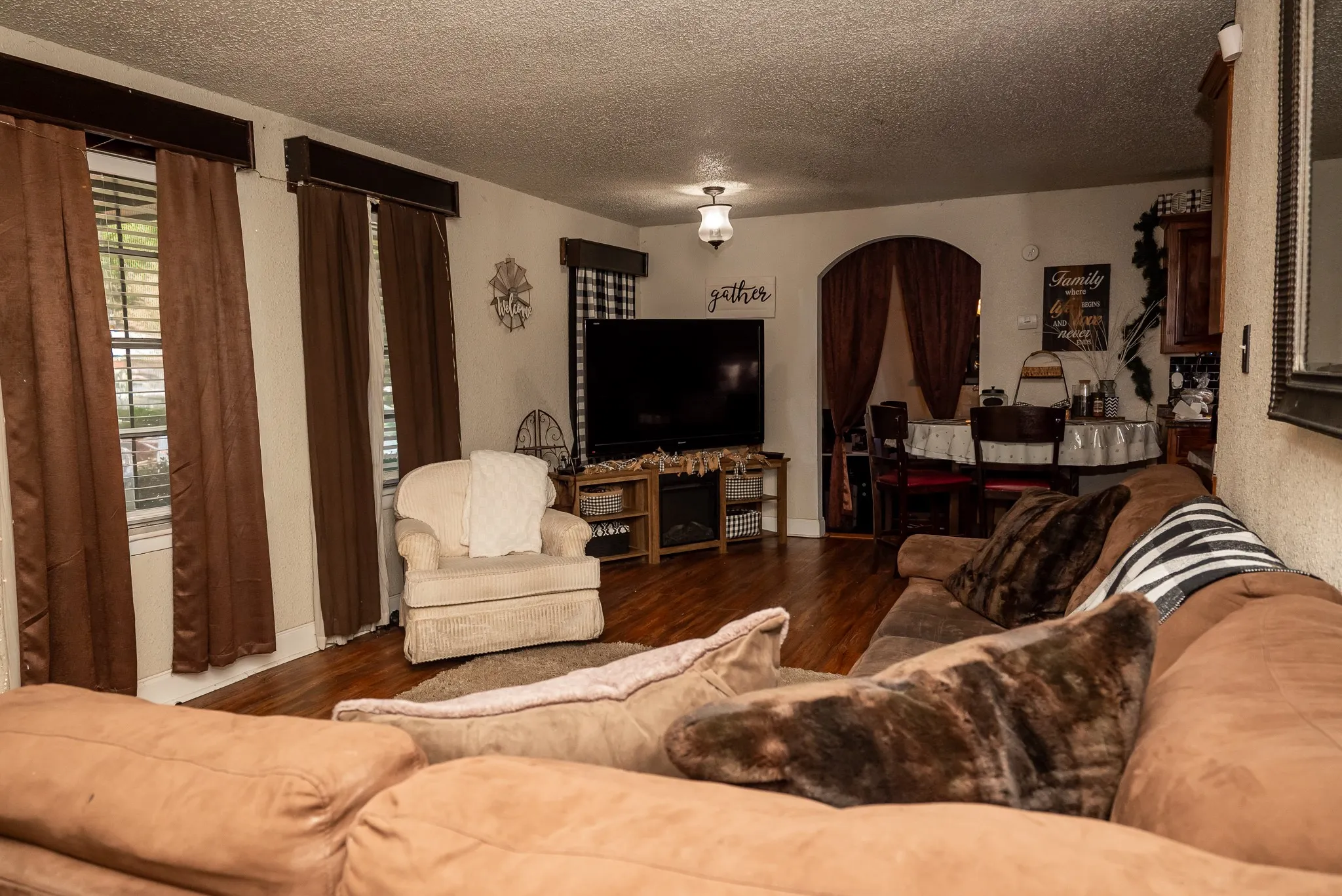 Living area featuring wood-finish flooring, textured ceilings, and a prominent arched entryway