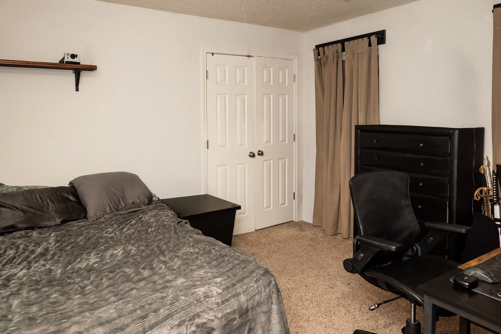 Neutral carpeting, double-panel closet doors, and wall-mounted shelving